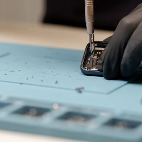 A technician carefully repairing a phone's internal components
